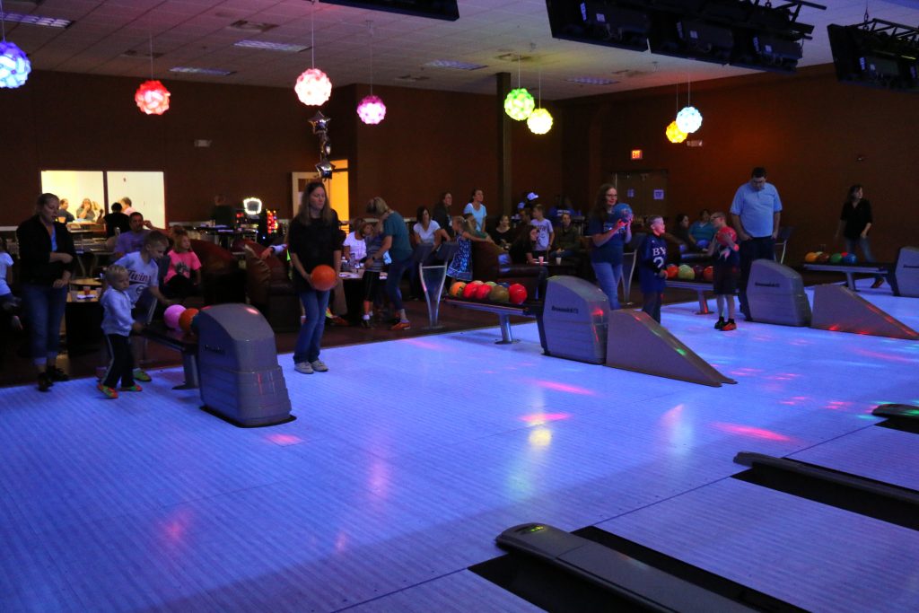 Company event at a bowling alley showing a large group of people bowling
