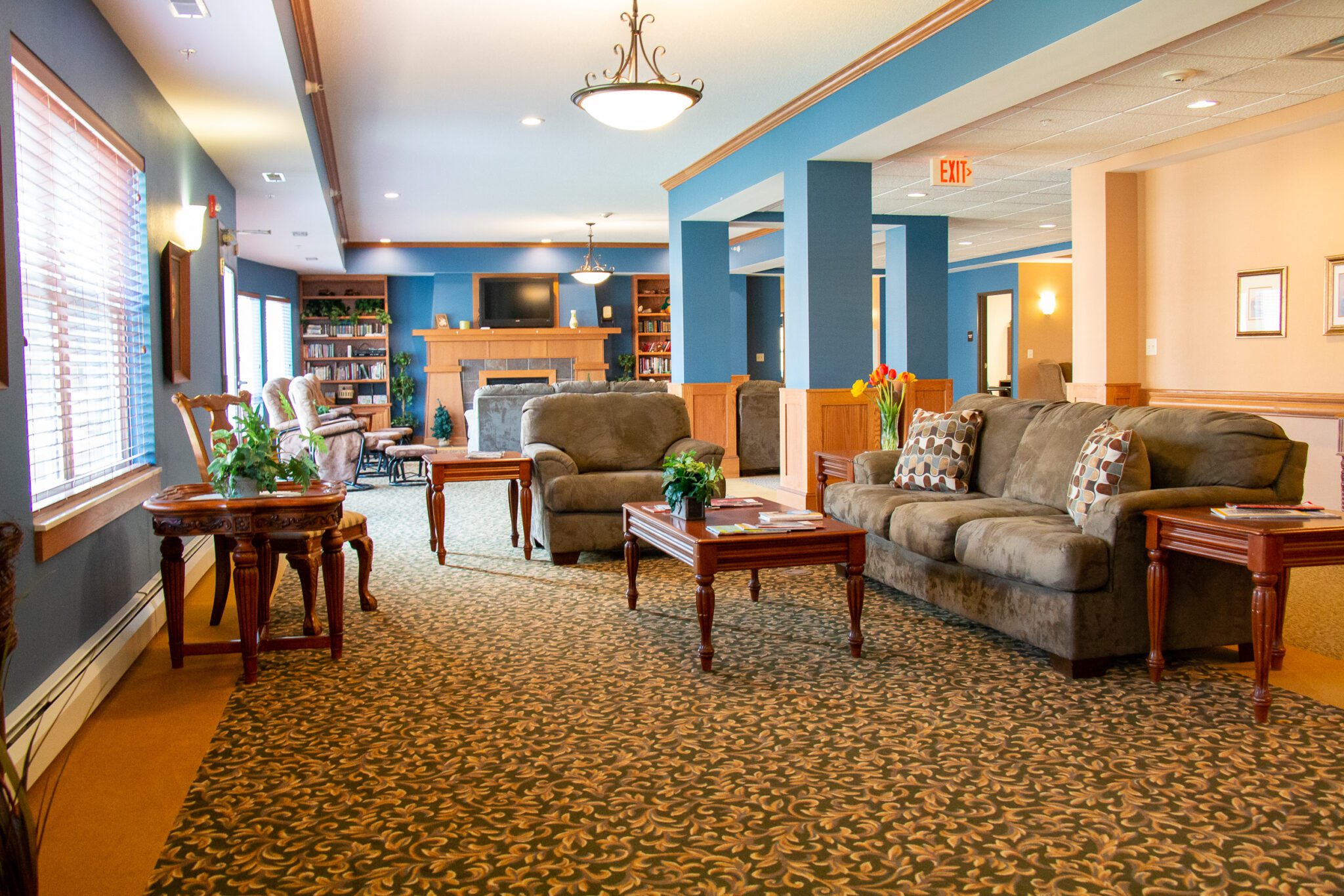 Eldercare of Bemidji community lounge with sofas, tables, and shelves of books.