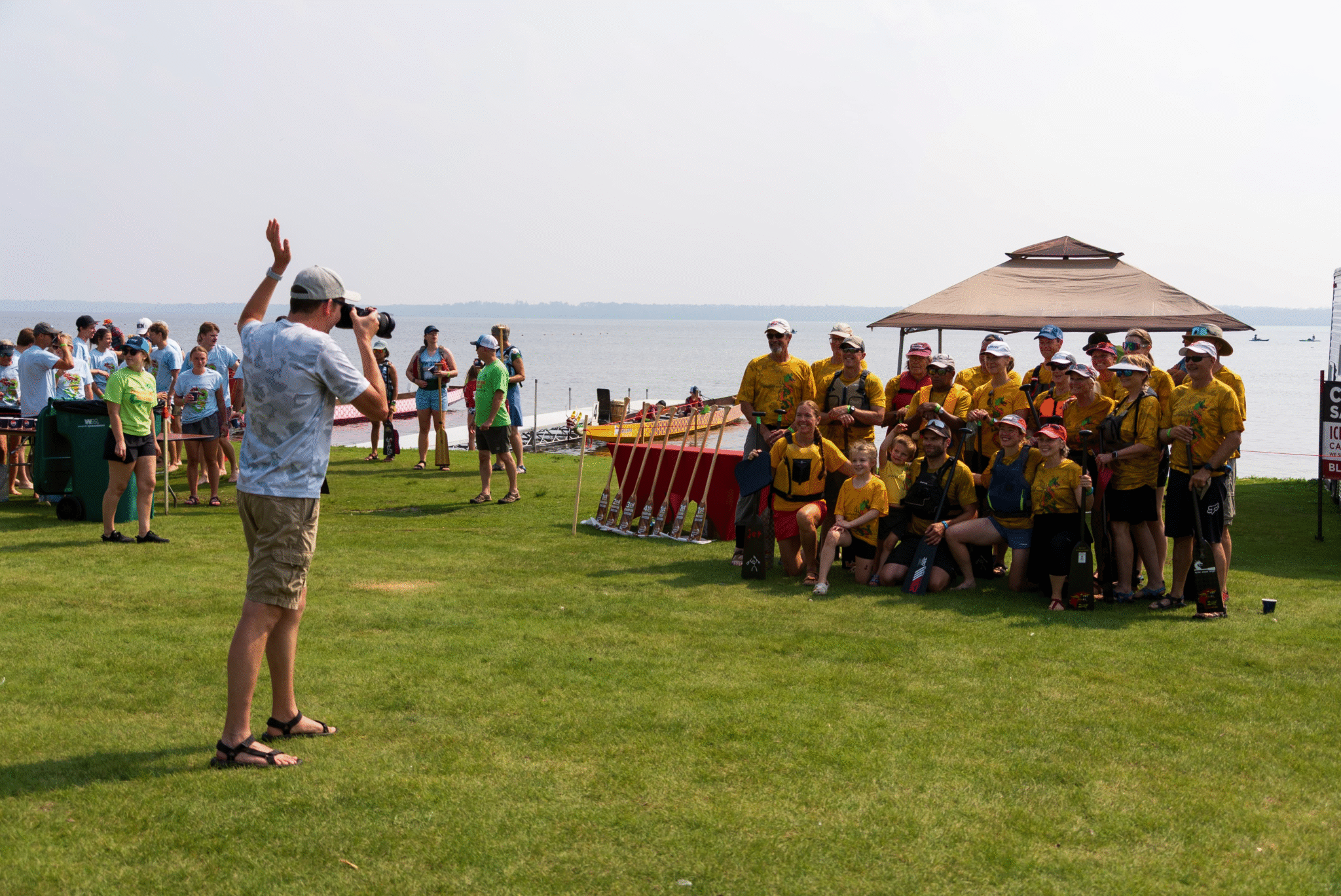 Pinnacle Marketing Group employee photographing a dragon boat team at the Bemidji Dragon Boat Festival by the lakeshore.