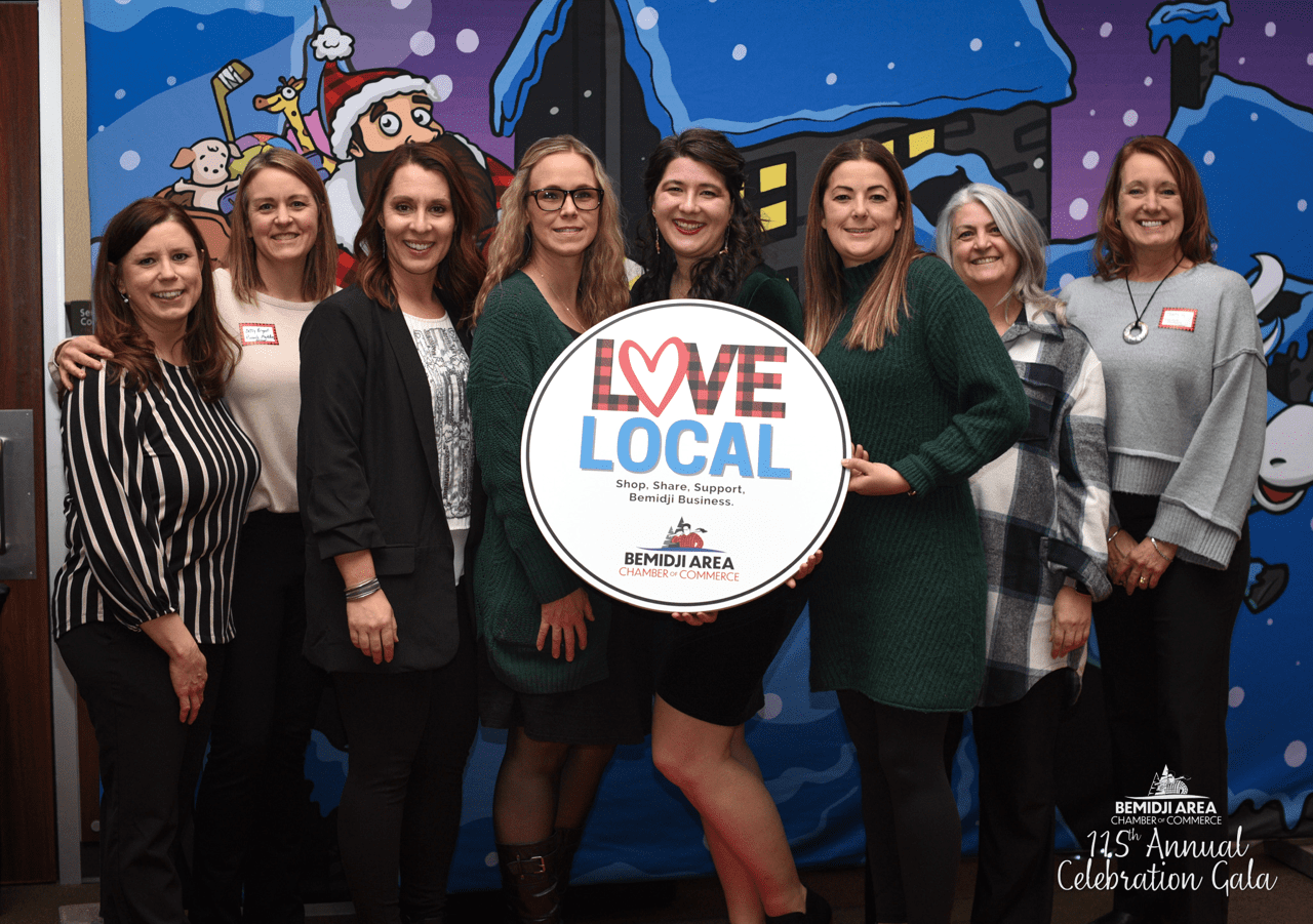 Group of Pinnacle Marketing Group employees smiling and holding a 